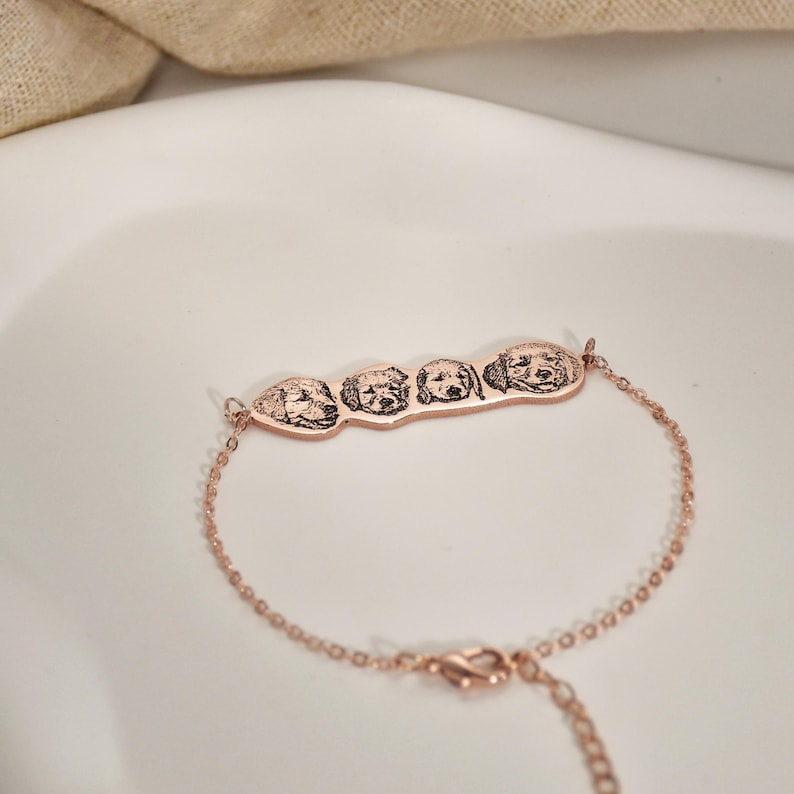 May include: A rose gold bracelet with a charm featuring four engraved dog faces.