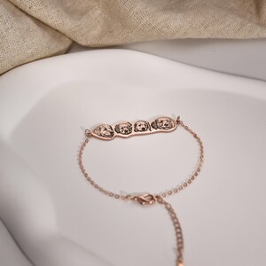 May include: A rose gold bracelet with a charm featuring four engraved dog faces.