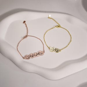 May include: Two gold bracelets with engraved pet portraits. One bracelet features a single cat and dog portrait, while the other bracelet features three dog portraits.