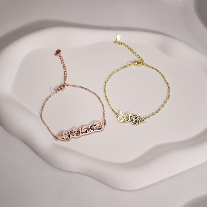 May include: Two gold bracelets with engraved pet portraits. One bracelet features a single cat and dog portrait, while the other bracelet features three dog portraits.