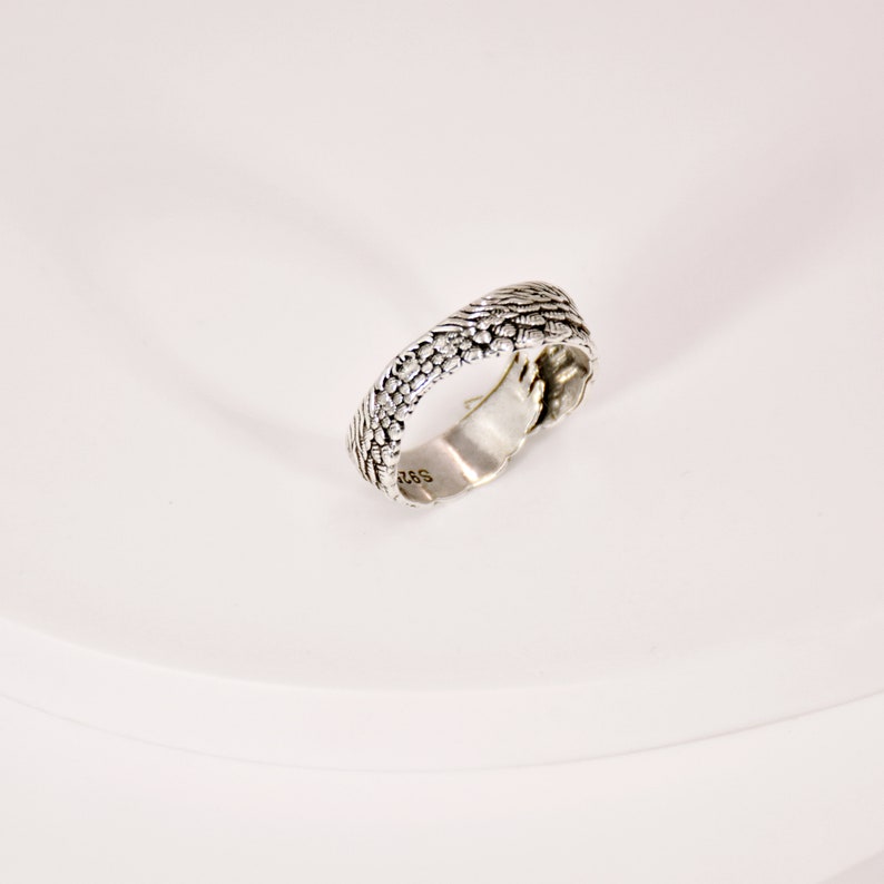 May include: A silver ring with a textured design. The ring is marked with "925" on the inside.