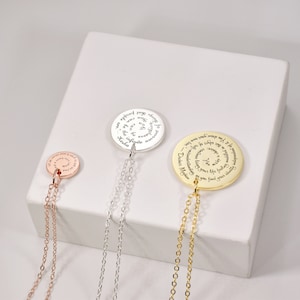 Puede incluir: Tres collares con colgantes en oro rosa, plata y oro. Cada colgante circular presenta texto grabado. El colgante de oro rosa tiene una cadena m&aacute;s corta. El colgante de plata tiene una cadena m&aacute;s larga. El colgante de oro tiene la cadena m&aacute;s larga.