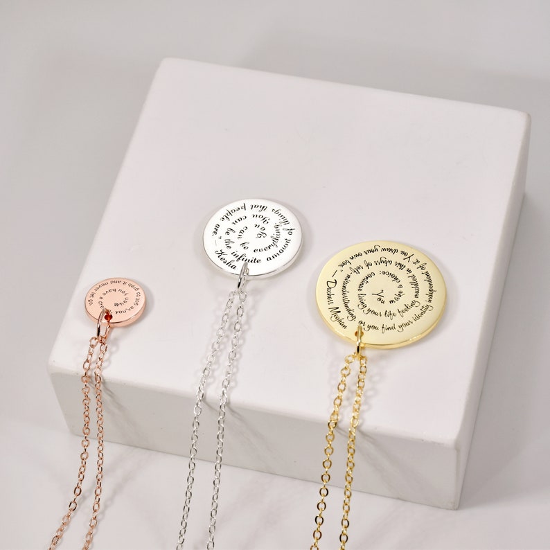 Puede incluir: Tres collares con colgantes en oro rosa, plata y oro. Cada colgante circular presenta texto grabado. El colgante de oro rosa tiene una cadena m&aacute;s corta. El colgante de plata tiene una cadena m&aacute;s larga. El colgante de oro tiene la cadena m&aacute;s larga.