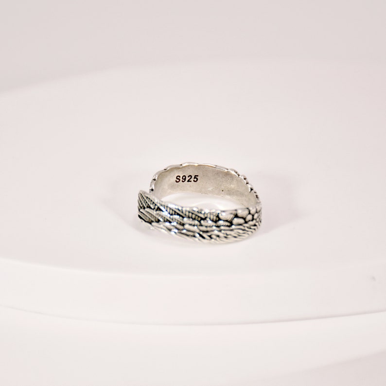May include: A silver ring with a textured design. The ring is marked with the number "S925" on the inside.