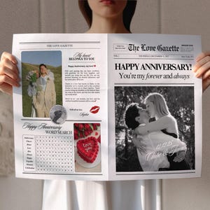 May include: A black and white photo of a couple embracing, with the text "Happy Anniversary! You're my forever and always" above the photo. The photo is framed in a newspaper-style layout with the title "The Love Gazette" and the date "Thursday, December 1, 2027". The newspaper also includes a word search puzzle and a photo of a red velvet cake with the words "Love You" written in white icing.