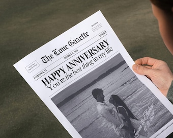 May include: A black and white newspaper with the headline "HAPPY ANNIVERSARY You're the best thing in my life". The newspaper is dated December 11, 20XX and has a photo of a couple on the beach.