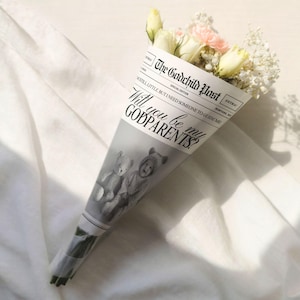 May include: A bouquet of white and pink flowers wrapped in a newspaper-style cone. The cone features the text "The Godchild Post" and "Will you be my GODPARENTS?" with a black and white image of two children.