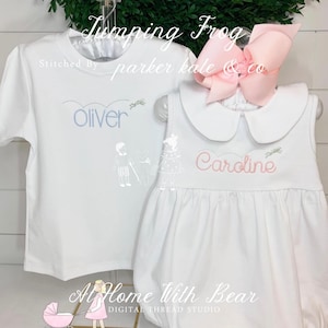 May include: A white children's outfit set with the text "Jumping Frog". The set includes a short-sleeved shirt embroidered with "Oliver" in blue and a romper embroidered with "Caroline" in pink. A large pink bow is attached to the romper.