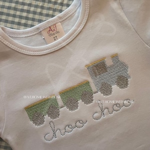 May include: White toddler t-shirt with a gray and green train design and the text "choo choo" in gray. The shirt has a tag that says "AJ Blanks 2T".