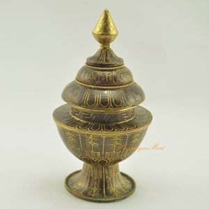 May include: A gold and brown metal incense burner with intricate designs. The burner has a rounded base and a domed top with a pointed finial.