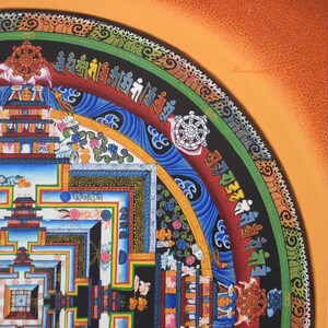 May include: A detailed, colorful painting featuring a geometric design with intricate patterns and symbols. The artwork includes a variety of colors, including blue, red, green, and gold, with a central focus on a circular mandala design. The painting has a spiritual or cultural theme.