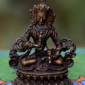 Peut inclure: Une petite statue en bronze d'une divinité assise en position méditative. La statue est finement détaillée avec une couronne, des bijoux et une fleur de lotus dans la main de la divinité.