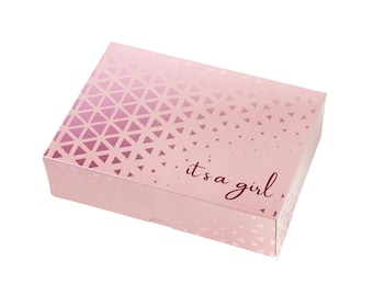 Könnte beinhalten: Eine rosa Geschenkbox mit geometrischem Muster und dem Text "it's a girl" auf der Vorderseite.