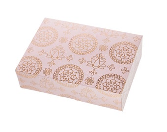 Könnte beinhalten: Eine rosa Geschenkbox mit einem goldenen Mandala-Muster. Die Box ist geschlossen und hat ein dekoratives Design.