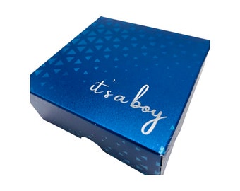 Könnte beinhalten: Eine blaue Geschenkbox mit einem weißen geometrischen Muster und dem Text "it's a boy" in silbernen Buchstaben.