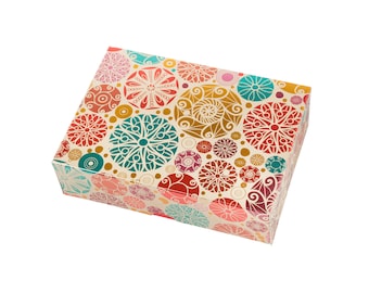Könnte beinhalten: Eine dekorative Geschenkbox mit einem farbenfrohen Muster aus Kreisen und Spiralen. Die Kreise sind in Rot-, Rosa-, Blau-, Grün- und Goldtönen gehalten. Der Hintergrund ist cremefarben.
