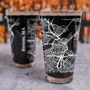 May include: Two clear glass beer mugs with black liquid inside. The mugs feature a white outline of a map of Boston, Massachusetts with street names and landmarks.