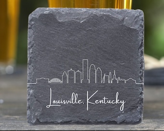 May include: A black slate coaster with a white outline of the Louisville, Kentucky skyline and the text "Louisville, Kentucky".