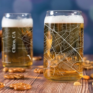May include: Two clear glass beer mugs with a city map design. The mugs are filled with a golden-colored beverage. The map design includes the text "Chico, CA" on one mug and "Barber" and "Bidwell" on the other mug.