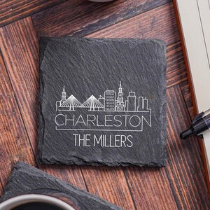 May include: Black slate coaster with a white outline of the Charleston skyline and the text "Charleston" and "The Millers".