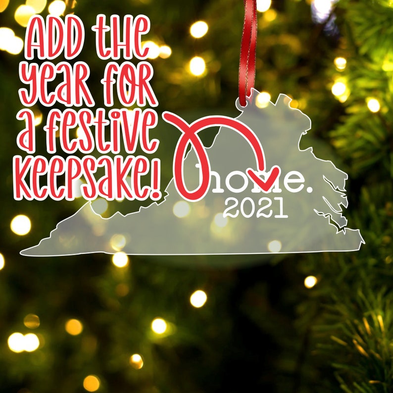 May include: A clear acrylic Christmas ornament shaped like the state of Virginia. The ornament has a red ribbon and the text "Home. 2021" on it. The text "Add the year for a festive keepsake!" is printed on the ornament.