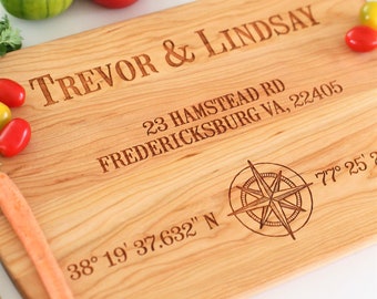 May include: Personalized wooden cutting board with the names "Trevor & Lindsay", an address, and coordinates engraved on it. The board features a compass design.
