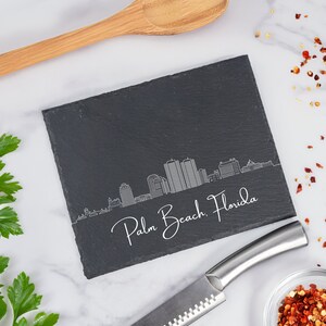 May include: Black slate serving tray with a white outline of the Palm Beach, Florida skyline. The tray is perfect for serving cheese, crackers, or other appetizers.