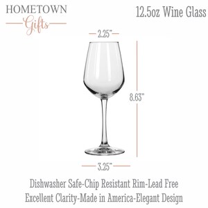May include: A clear 12.5oz wine glass with a stem and circular base. Text includes HOMETOWN Gifts, 12.5oz Wine Glass, and Dishwasher Safe-Chip Resistant Rim-Lead Free Excellent Clarity-Made in America-Elegant Design. Dimensions are 2.25 inches wide and 8.63 inches tall.