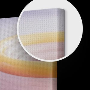 Puede incluir: Primer plano de una impresi&oacute;n en lienzo con una superficie suave y texturizada. La obra de arte presenta un degradado de colores, que transita del rosa al amarillo y al lavanda. El lienzo est&aacute; estirado sobre un marco de madera.