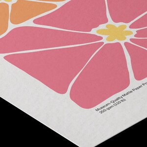 Puede incluir: Primer plano de una impresi&oacute;n con un dise&ntilde;o floral estilizado. La obra presenta grandes flores abstractas en tonos rosa, naranja y amarillo sobre un fondo blanco. El papel est&aacute; etiquetado como "Museum-Quality Matte Paper" y pesa 250 g/m&sup2;.