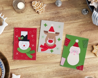 May include: Three handmade felt Christmas cards featuring a snowman, reindeer, and Santa Claus. The cards are decorated with festive colors and patterns.