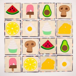Può includere: Un set di 16 quadrati di feltro con varie immagini di cibo, tra cui anguria, gelato, avocado, fungo, limone, uovo, cupcake e formaggio. I quadrati sono disposti in una griglia 4x4 su uno sfondo bianco.