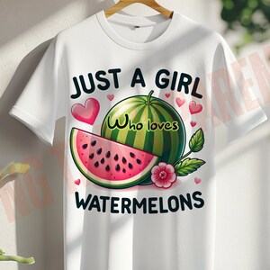 Op de afbeelding: Wit T-shirt met de tekst "Just a girl who loves watermelons" in zwart. Het shirt heeft een cartoon watermeloen met rood vruchtvlees en zwarte pitten, een roze bloem en groene bladeren.