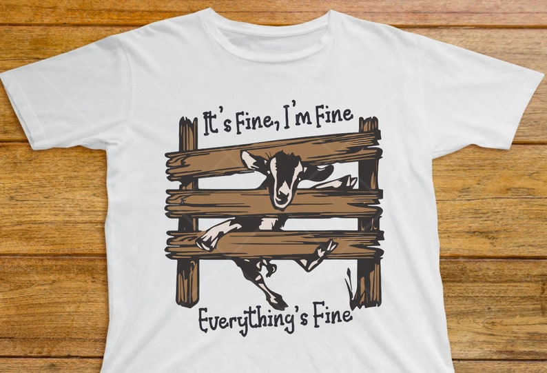 May include: White t-shirt with a brown wooden fence and a goat sticking its head through the fence. The text "It's Fine, I'm Fine Everything's Fine" is printed on the shirt.