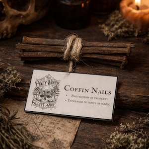 May include: A bundle of rusty coffin nails tied with twine, accompanied by a business card from "The Piney Woods Oddity Shop." The card lists "Protection of Property" and "Increased Potency of Magic." The scene is set on a dark wooden surface with a skull and candle.