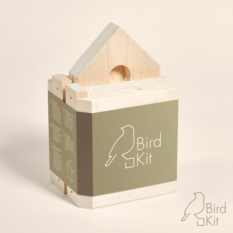 K&ouml;nnte beinhalten: Ein Vogelhaus-Bausatz aus Holz mit Anleitung. Der Bausatz ist in einer Schachtel mit einem gr&uuml;nen Etikett verpackt, auf dem "Bird Kit" steht und eine stilisierte Vogel-Illustration abgebildet ist.