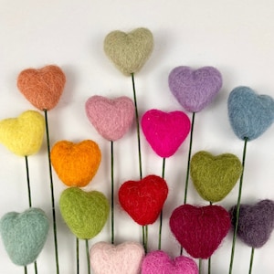 Puede incluir: Un ramo de 16 corazones de fieltro en tallos de alambre. Los corazones son de varios colores, incluyendo rojo, rosa, verde, azul, morado, naranja, amarillo y marr&oacute;n.