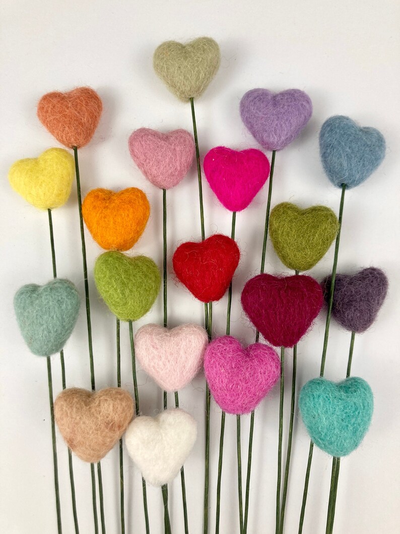 Puede incluir: Un ramo de 16 corazones de fieltro en tallos de alambre. Los corazones son de varios colores, incluyendo rojo, rosa, verde, azul, morado, naranja, amarillo y marr&oacute;n.