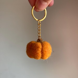 May include: A small orange felt pumpkin keychain with a gold chain and ring.
