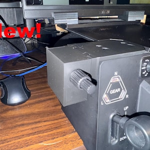 May include: A black control panel with a gear selector, a knob, and a lever. The panel has the words "GEAR", "UP", and "DOWN" printed on it.