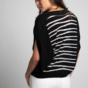 Puede incluir: Un top de punto de rayas blancas y negras con un corte holgado y mangas cortas. El top est&aacute; hecho de una tela suave y ligera y tiene un estilo relajado y casual.