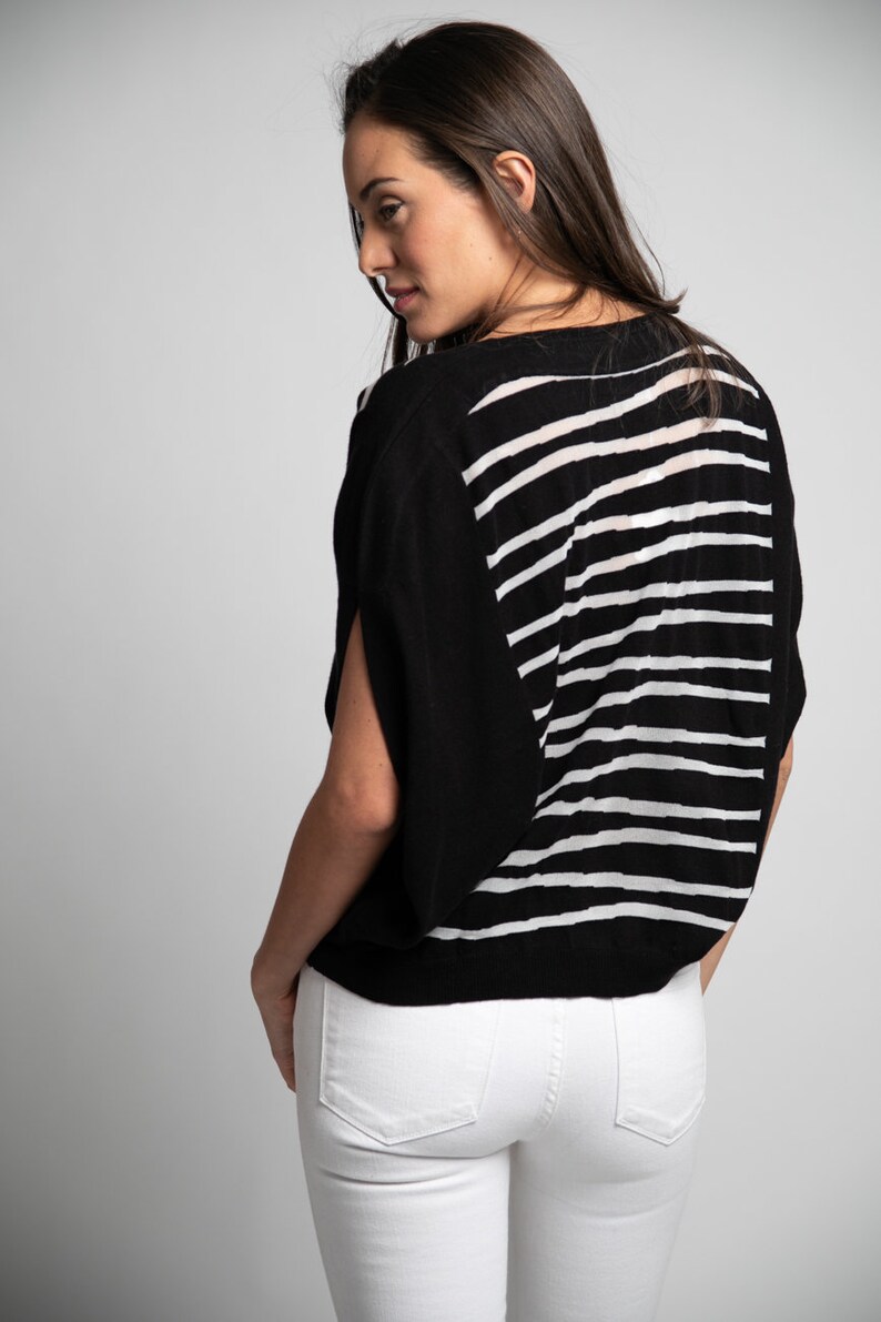 Puede incluir: Un top de punto de rayas blancas y negras con un corte holgado y mangas cortas. El top est&aacute; hecho de una tela suave y ligera y tiene un estilo relajado y casual.