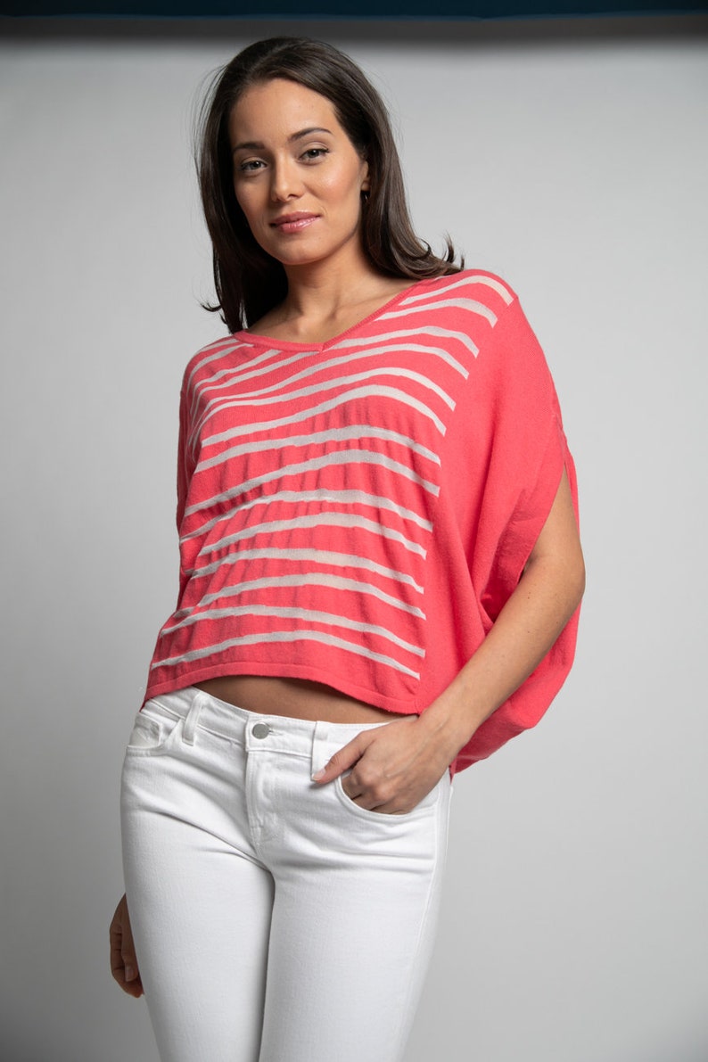 Puede incluir: Una mujer lleva una camisa de rayas rosa y blancas con un corte holgado y un dobladillo recortado. Tambi&eacute;n lleva pantalones vaqueros blancos.