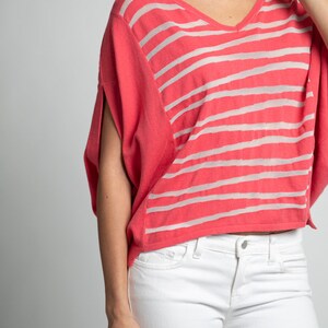 Puede incluir: Un top de punto de rayas coral con cuello en V y mangas cortas. El top es corto y tiene un corte holgado.