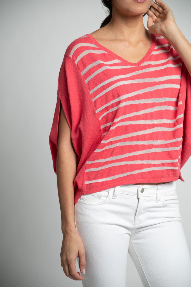 Puede incluir: Un top de punto de rayas coral con cuello en V y mangas cortas. El top es corto y tiene un corte holgado.