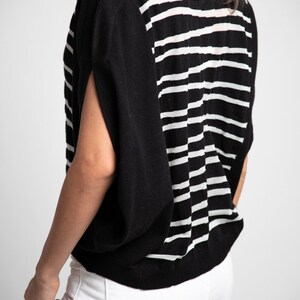 Puede incluir: Un top de punto de rayas blancas y negras con un corte holgado y mangas cortas.