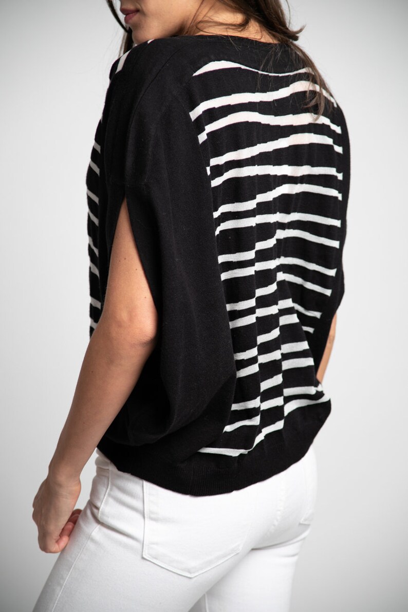 Puede incluir: Un top de punto de rayas blancas y negras con un corte holgado y mangas cortas.