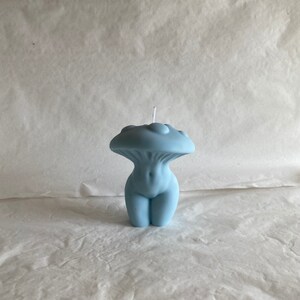 K&ouml;nnte beinhalten: Eine hellblaue Kerze in Form einer menschlichen Figur mit einem pilzf&ouml;rmigen Oberteil. Die Kerze hat einen wei&szlig;en Docht.