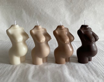 May include: Four sculpted candles in the shape of a pregnant woman's torso. The candles are in various shades of brown, from light to dark.