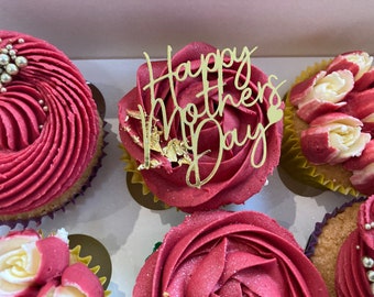 May include: Six cupcakes decorated with pink frosting and various toppings. One cupcake has a gold "Happy Mother's Day" topper.